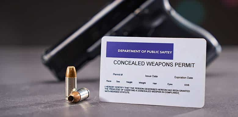 Gun and bullets next to concealed weapons permit card